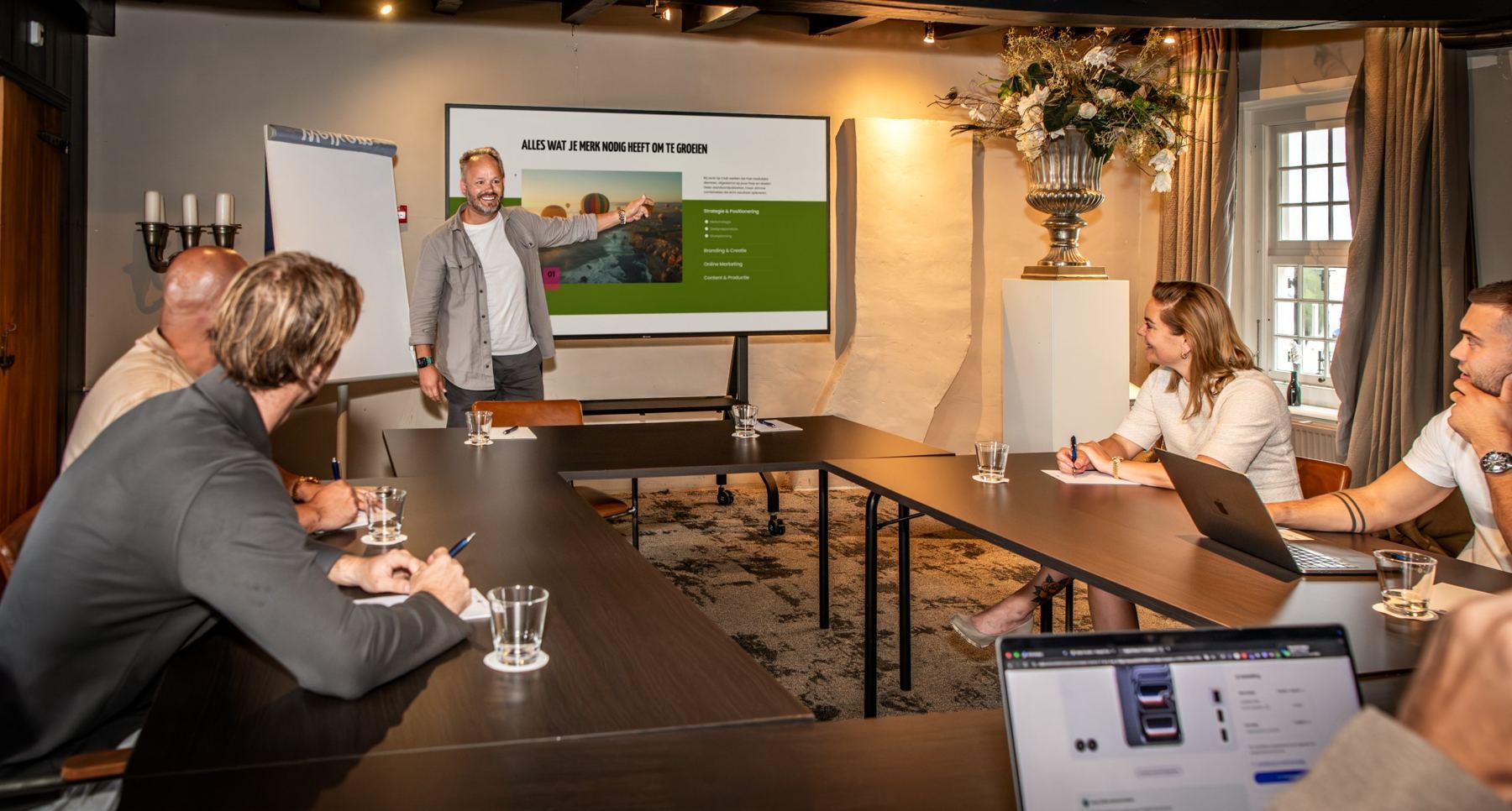 Een strategische sessie van Level Up Club: een teamlid presenteert aan klanten rond een vergadertafel
