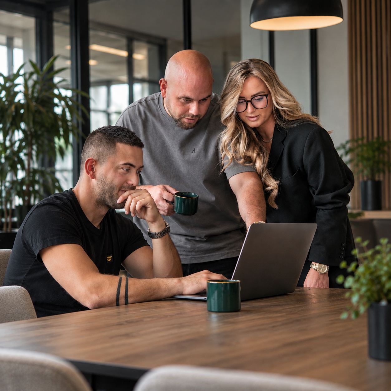 Drie teamleden van Level Up Club werken samen aan een laptop